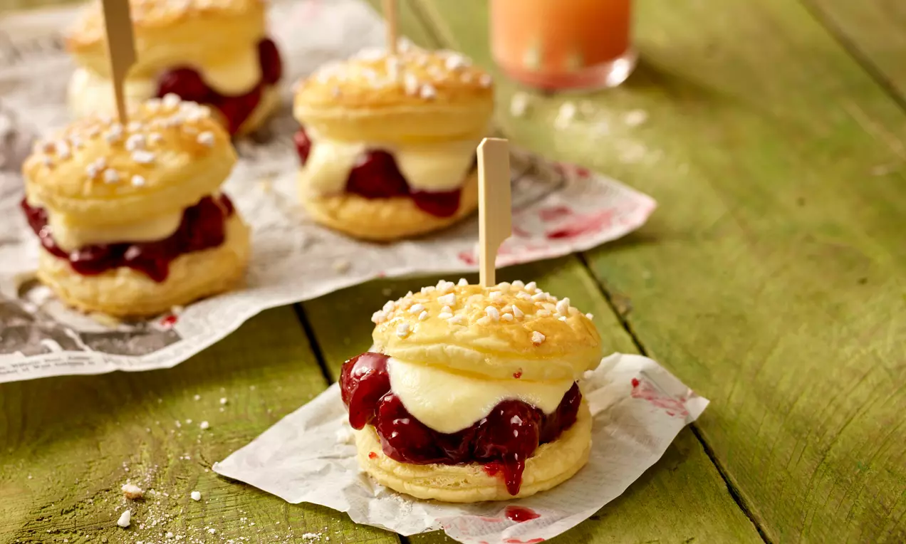 Mini deserti sa zlatnosmeđim lisnatim pecivom, kremom od vanilije i crvenim voćnim nadjevom, posuti krupnim bijelim šećerom, na papiru