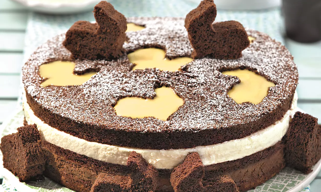 Čokoladna torta s dva tamna biskvita, svijetlim slojem kreme, izrezanim motivima zeca, preljevom od žutog likera i šećerom u prahu